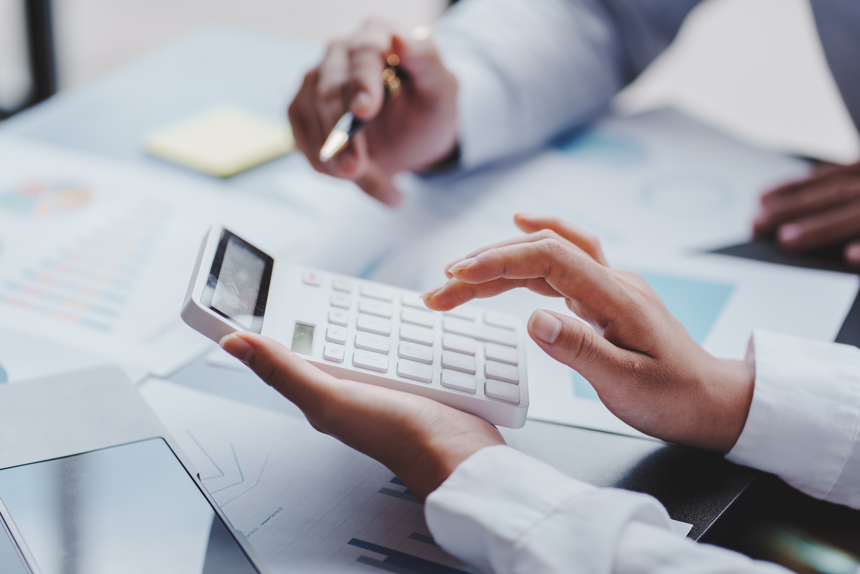 Business Meeting Calculating Financials with Calculator and Graphs